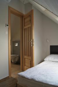 1 dormitorio con 1 cama y puerta que conduce a un baño en Apartament Zacisze, en Jaworki