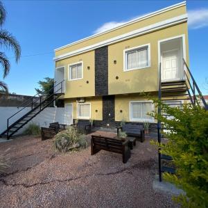 a yellow house with benches in front of it at Apartamento Lo de Ana in Termas de Río Hondo +6 photos