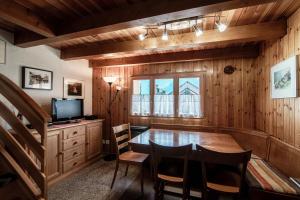 a dining room with a table and a television at Baita dal Gat by Quokka 360 - Stylish Wooden Chalet Retreat in Faido in Sobrio