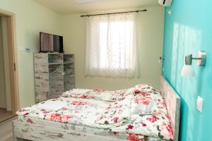 1 dormitorio con 1 cama con sábanas florales y ventana en Alfa Apartman, en Mórahalom