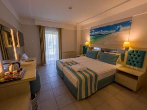 a hotel room with a large bed with a painting on the wall at AQI Hydros Club in Kemer