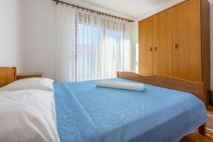 a bedroom with a bed with a blue comforter and a window at Apartments Josip in Novi Vinodolski