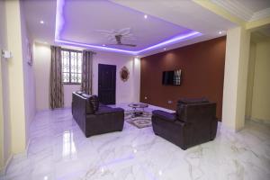 ein Wohnzimmer mit 2 Stühlen und einem Deckenventilator in der Unterkunft Executive 3-Bed Furnished Apartment in Kwashieman in Accra