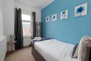a bedroom with a bed with blue walls and a window at Spacious & Unique Family and Contractor House & Parking & A1 Road in Grantham