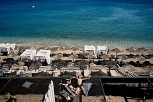 two people sitting on a beach with umbrellas at Artemis Seaside Resort in Paliochori