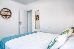 een witte slaapkamer met een bed en een spiegel bij Chez Carmen Allegranza - Pool View - By Lanzarote Vacation Homes in Puerto del Carmen