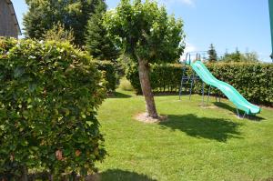 スタヴロにあるLes Mélèzesの木の横に緑の滑り台がある遊び場