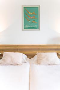 2 Betten mit weißen Kissen und einem Bild an der Wand in der Unterkunft Appart'hotel Victoria Garden Pau in Pau