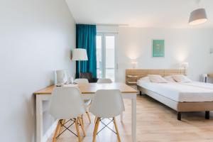 Un dormitorio con una cama y una mesa y sillas. en Appart'hotel Victoria Garden Pau, en Pau