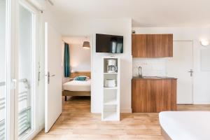 a room with a kitchen and a bedroom with a bed at Appart'hotel Victoria Garden Pau in Pau