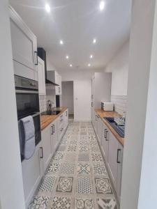 a kitchen with white cabinets and a tile floor at Highly Modern home, 3 bed, close to the Lake District in Barrow in Furness