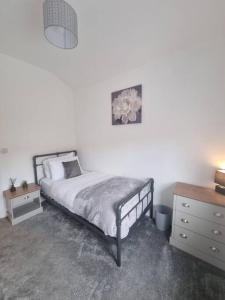 um quarto com uma cama e uma cómoda e uma mesa de cabeceira em Highly Modern home, 3 bed, close to the Lake District em Barrow in Furness