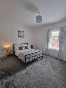a white bedroom with a bed and a window at Highly Modern home, 3 bed, close to the Lake District in Barrow in Furness