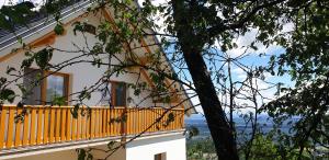 una casa gialla con balcone e albero di Apartma pri Boštjanu a Škofja Loka