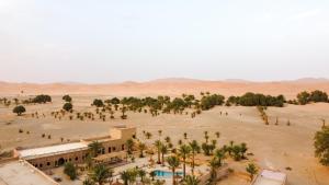eine Luftansicht auf eine Wüste mit Palmen und einem Gebäude in der Unterkunft RiadSuerteloca Merzouga in Merzouga