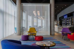 a lobby with colorful chairs and tables on a rug at Aloft London Excel in London