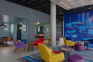 a waiting room with colorful chairs and tables at Aloft London Excel in London