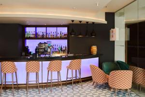 a bar in a restaurant with chairs around it at Aloft London Excel in London