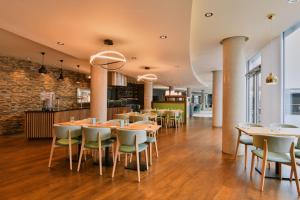 a restaurant with wooden tables and chairs and a brick wall at Aloft London Excel in London