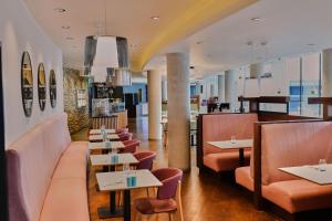 a restaurant with tables and chairs and a bar at Aloft London Excel in London
