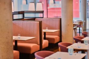 a restaurant with tables and chairs with glasses on them at Aloft London Excel in London