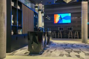 a lobby with a bar with a tv on the wall at Aloft London Excel in London
