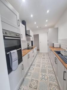 a kitchen with white cabinets and a tile floor at Highly Modern home, 3 bed, close to the Lake District in Barrow in Furness