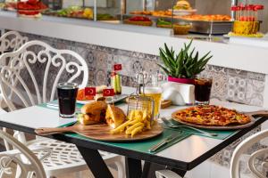 a table with a plate of food and a pizza at AQI Hydros Club in Kemer