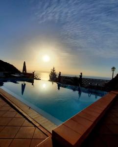 a large swimming pool with the sunset in the background at VILLA ZEN TAORMINA in Taormina