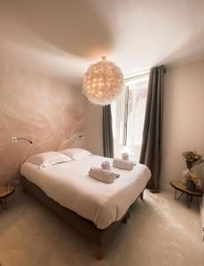 a bedroom with a large bed with a chandelier at Hôtel Restaurant "La Petite Auberge" in Bourg-Saint-Maurice