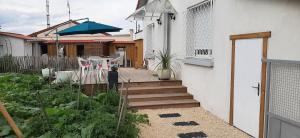 a house with a porch with a wooden staircase and an umbrella at Maison ville agréable in Riorges