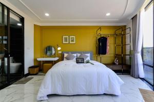 a bedroom with a bed and a yellow wall at Aura Apartment Da Lat in Da Lat