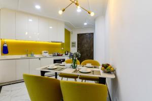 a kitchen with a table and yellow chairs in a kitchen at Aura Apartment Da Lat in Da Lat