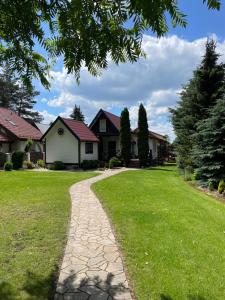 a walkway in front of a yard with houses at Domek letniskowy Sosenka in Woryty