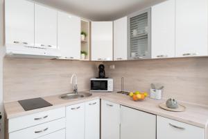 a white kitchen with a sink and a microwave at Apartments Anđela in Skradin