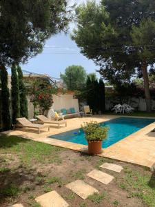 einen Pool in einem Garten mit Bänken und Bäumen in der Unterkunft La Casita Bianca in El Campello