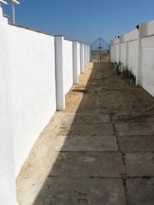 a long sidewalk next to a white wall at El Chalet in Punta Umbría