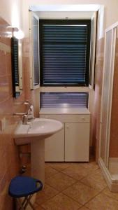 a bathroom with a sink and a window with a blue stool at Casa Valdese Rio Marina in Rio Marina