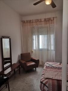 um quarto com uma cama, uma cadeira e uma janela em Bergantin 8 em Torrevieja