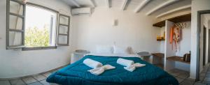 a bedroom with a blue bed with two white shoes on it at Soros Beach Antiparos in Agios Georgios