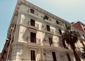 un grande edificio bianco con balconi e una palma di Palazzo Berardi a Taranto
