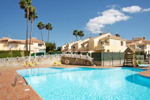 a large swimming pool with palm trees and houses at Bungalow Sonemar Sunshine in Maspalomas