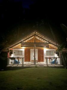 a house with two tables and chairs in the night at Nypa Style Resort Camiguin in Mambajao