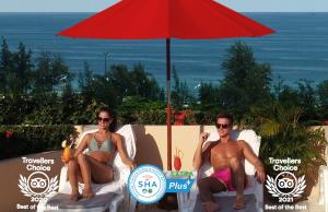 a man and a woman sitting in chairs under an umbrella at Pacific Club Resort in Karon Beach