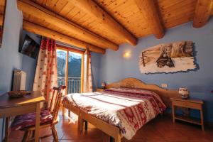 a bedroom with a bed and a table and a window at Agriturismo Belotti in Temù