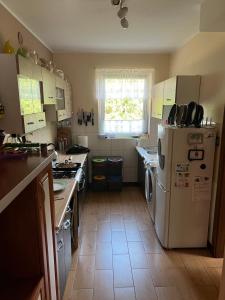 a kitchen with a white refrigerator and a window at Kaszuby- Domek całoroczny nad Jeziorem Gowidlińskim in Sulęczyno