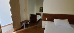 1 dormitorio con cama, silla y espejo en Pousada Villa Magnolia, en São João del Rei