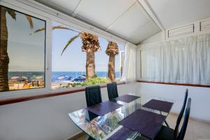 ein Esszimmer mit einem Tisch, Stühlen und Palmen in der Unterkunft Sea Front Costa Adeje Bungalow in Adeje
