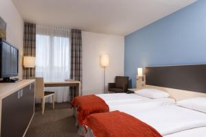 ボンにあるメルキュール ボン ハートベルクのベッド2台、薄型テレビが備わるホテルルームです。