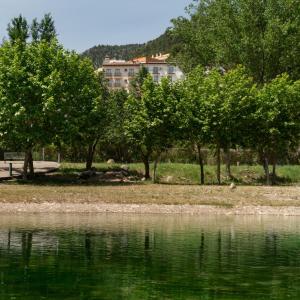 un grupo de árboles junto a un cuerpo de agua en Hotel Xauen, en Montanejos